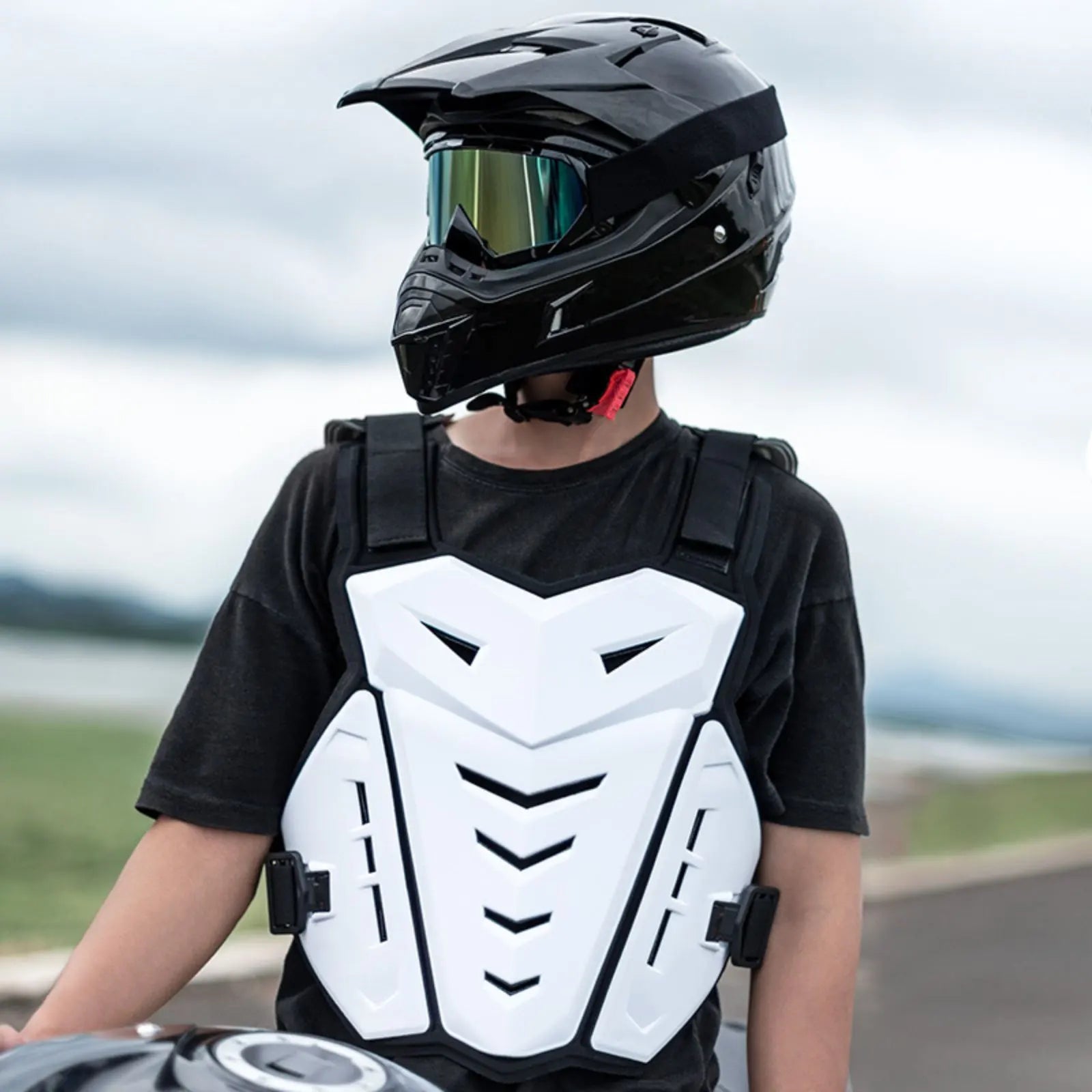 Pare pierre moto blanc porté par un jeune pilote casqué assis sur sa moto