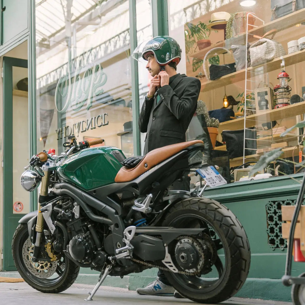 Casque jet heritage vert anglais porté par un motard devant un café-racer en ville