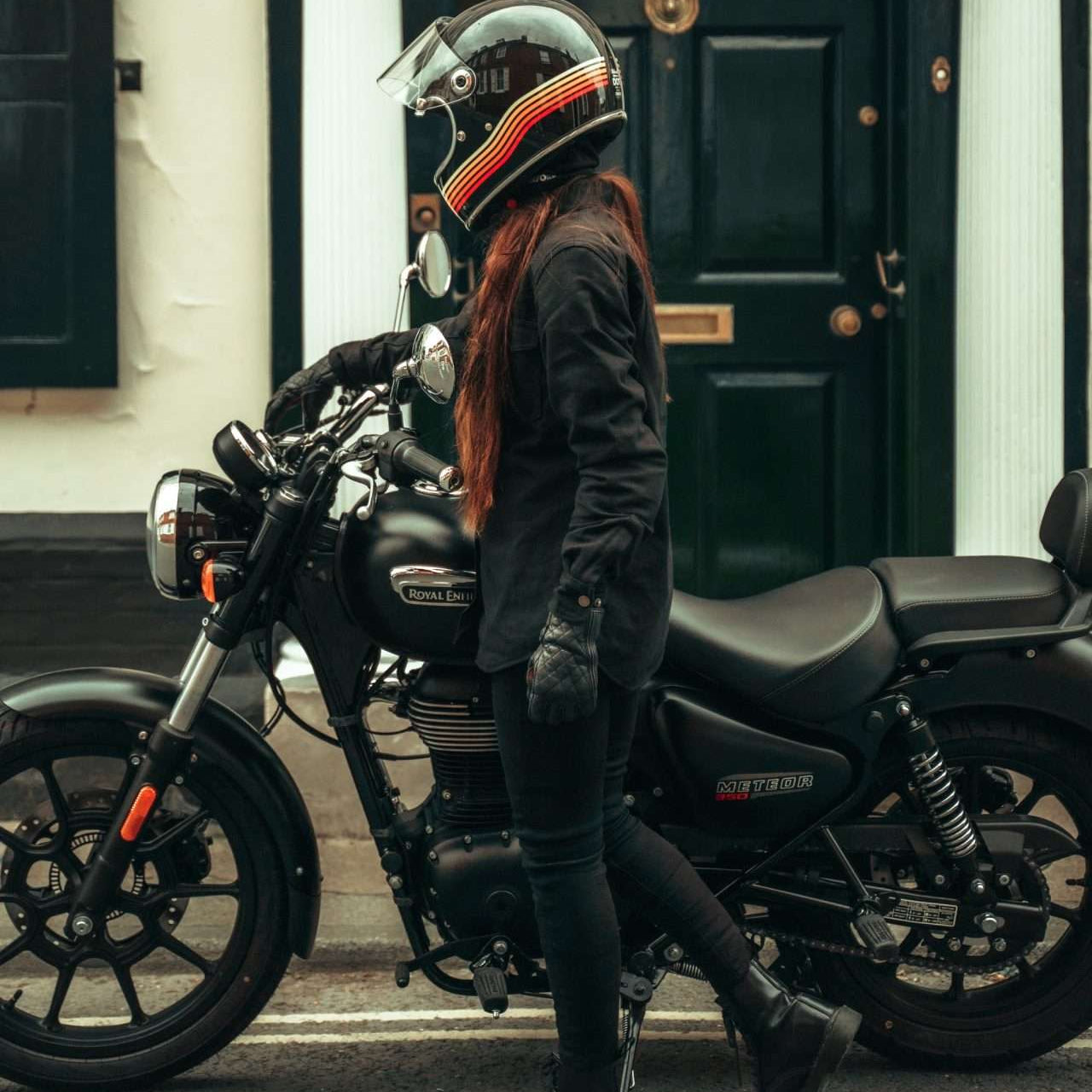 Motarde en jean moto femme SKADI noir devant une moto classique en ville