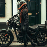 Motarde en jean moto femme SKADI noir devant une moto classique en ville
